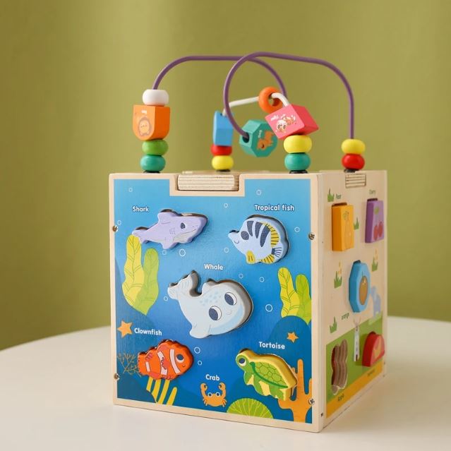 Cube en bois multi activités avec des animaux marins à encastrer et un circuit de perles colorées pour stimuler l'éveil et la coordination des jeunes enfants.