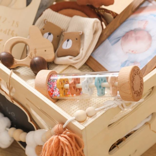 Bâton de pluie bébé, placé dans une boîte de naissance avec des jouets et souvenirs doux, conçu pour stimuler les sens de bébé avec ses perles colorées.