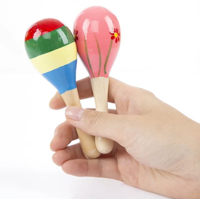 Main tenant deux maracas en bois bébé, l'un coloré de rayures et l'autre décoré de fleurs, parfaits pour encourager la motricité et l'éveil musical des jeunes enfants.