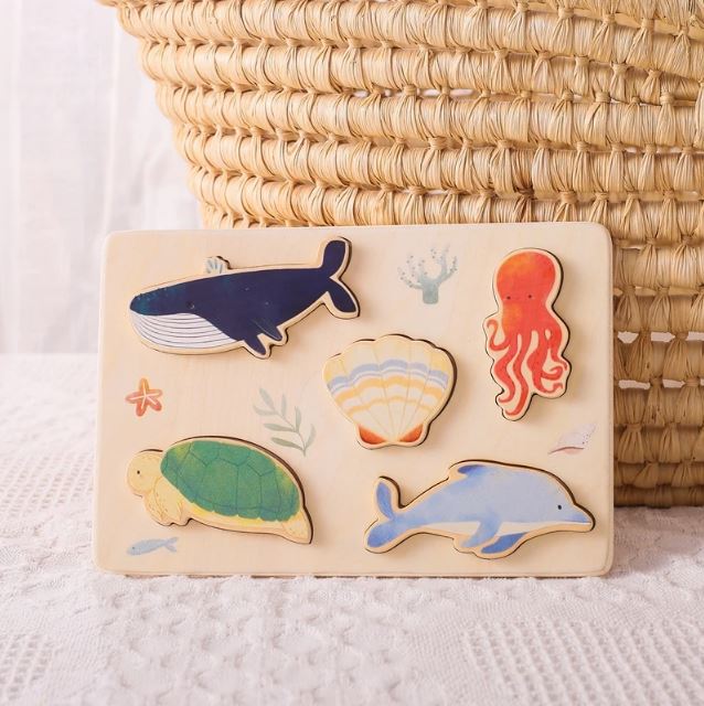 Puzzle animaux marins en bois avec des pièces représentant une baleine, un dauphin, une tortue, une pieuvre et une coquille, parfait pour développer la motricité des tout-petits.