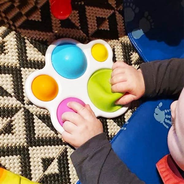 Pop it pour bébé manipulé par un enfant, offrant un jeu d'exploration tactile et sensoriel avec de grosses bulles faciles à presser pour les petites mains.