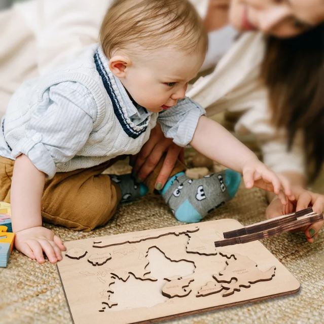 Enfant jouant avec un puzzle continent Montessori en bois, favorisant l'apprentissage des continents à travers une approche ludique et éducative.