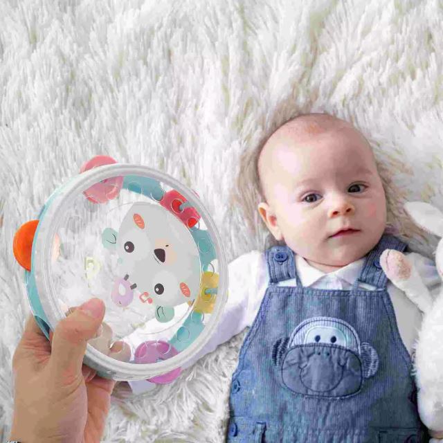 Bébé jouant avec un tambourin pour enfant, allongé sur une couverture douce, pour encourager l'éveil musical et la coordination.