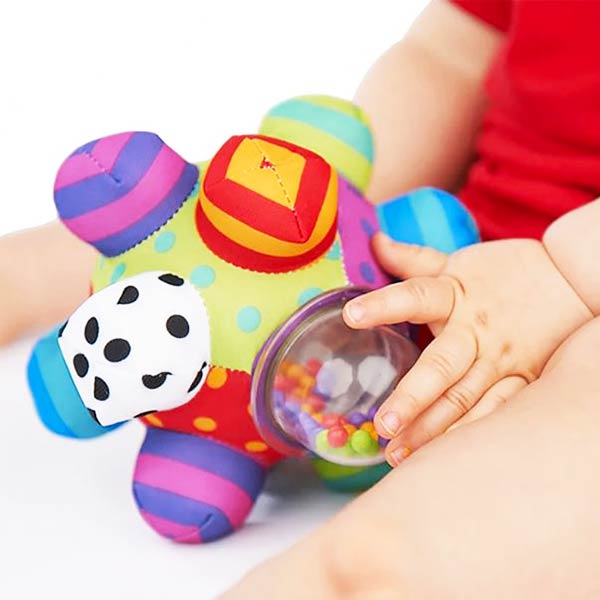 Bébé tenant une balle d'activité colorée avec des éléments interactifs pour développer la motricité et les sens.