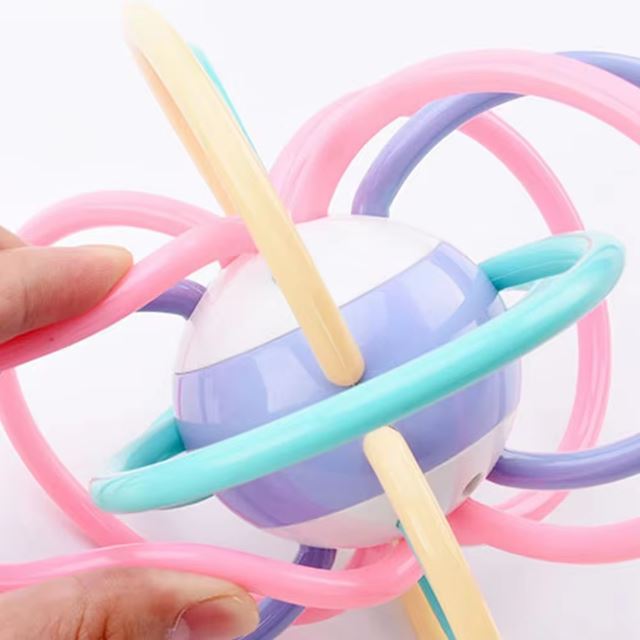 Zoom sur une balle sensorielle pour bébé en silicone conçu avec des anneaux colorés et souples, idéale pour le développement tactile et la coordination motrice.