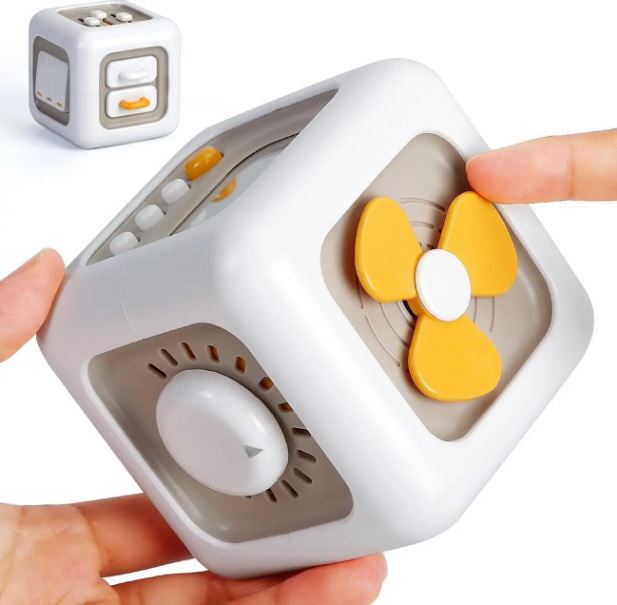 Cube sensoriel montessori interactif montrant une hélice jaune et un bouton rotatif, conçu pour encourager l'exploration tactile et la motricité fine chez les jeunes enfants.