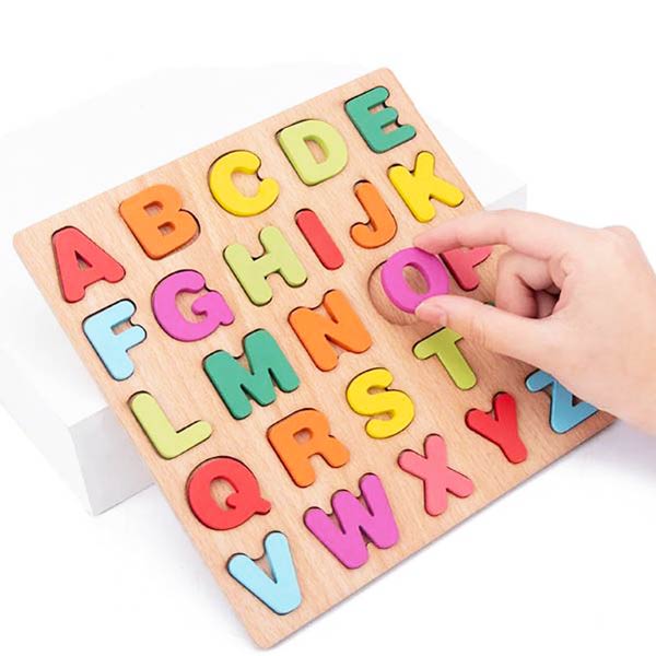 Puzzle alphabet en bois avec des lettres colorées dont une main manipule une des pièces.